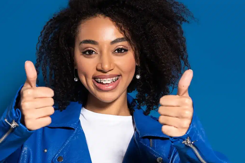 Smiling woman with braces and thumbs-up