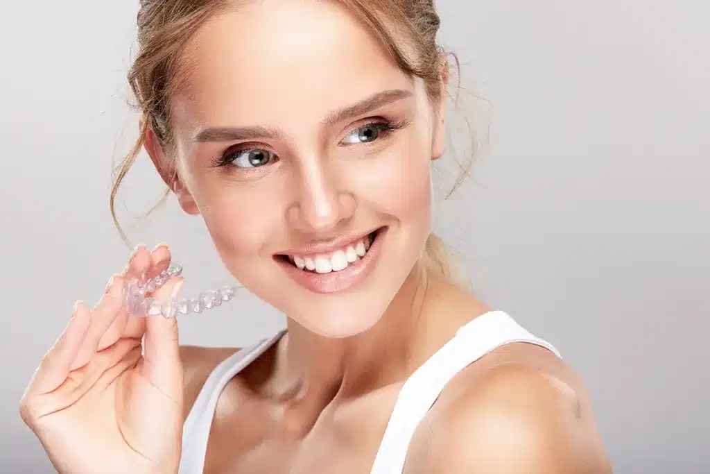 Smiling woman holding clear aligners