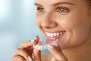 Smiling woman holding clear aligner
