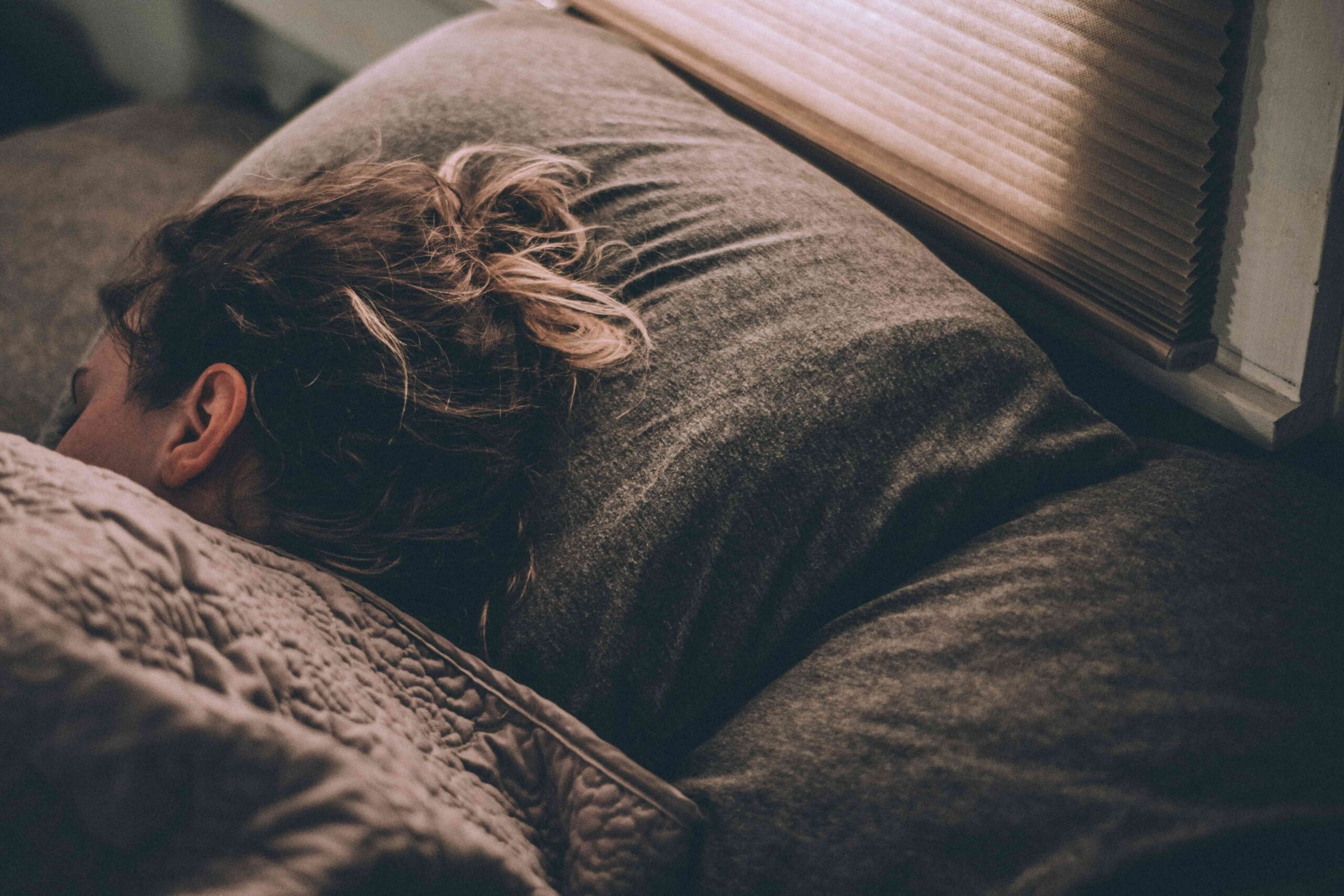 woman laying head on pillow in bed