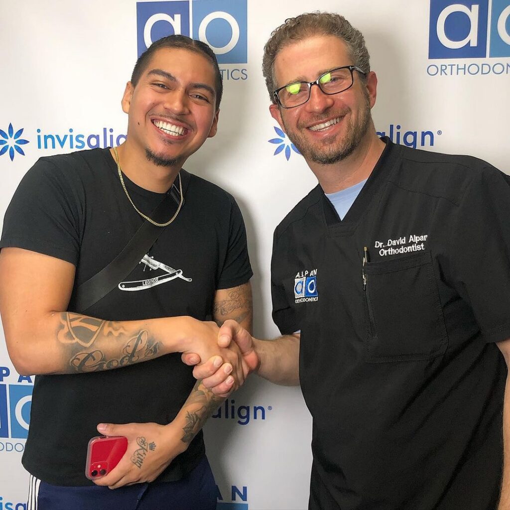Two men shaking hands, smiling.