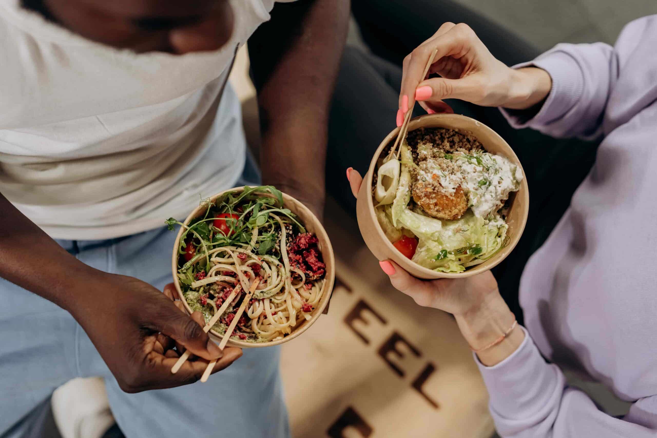 people holding healthy food bowls